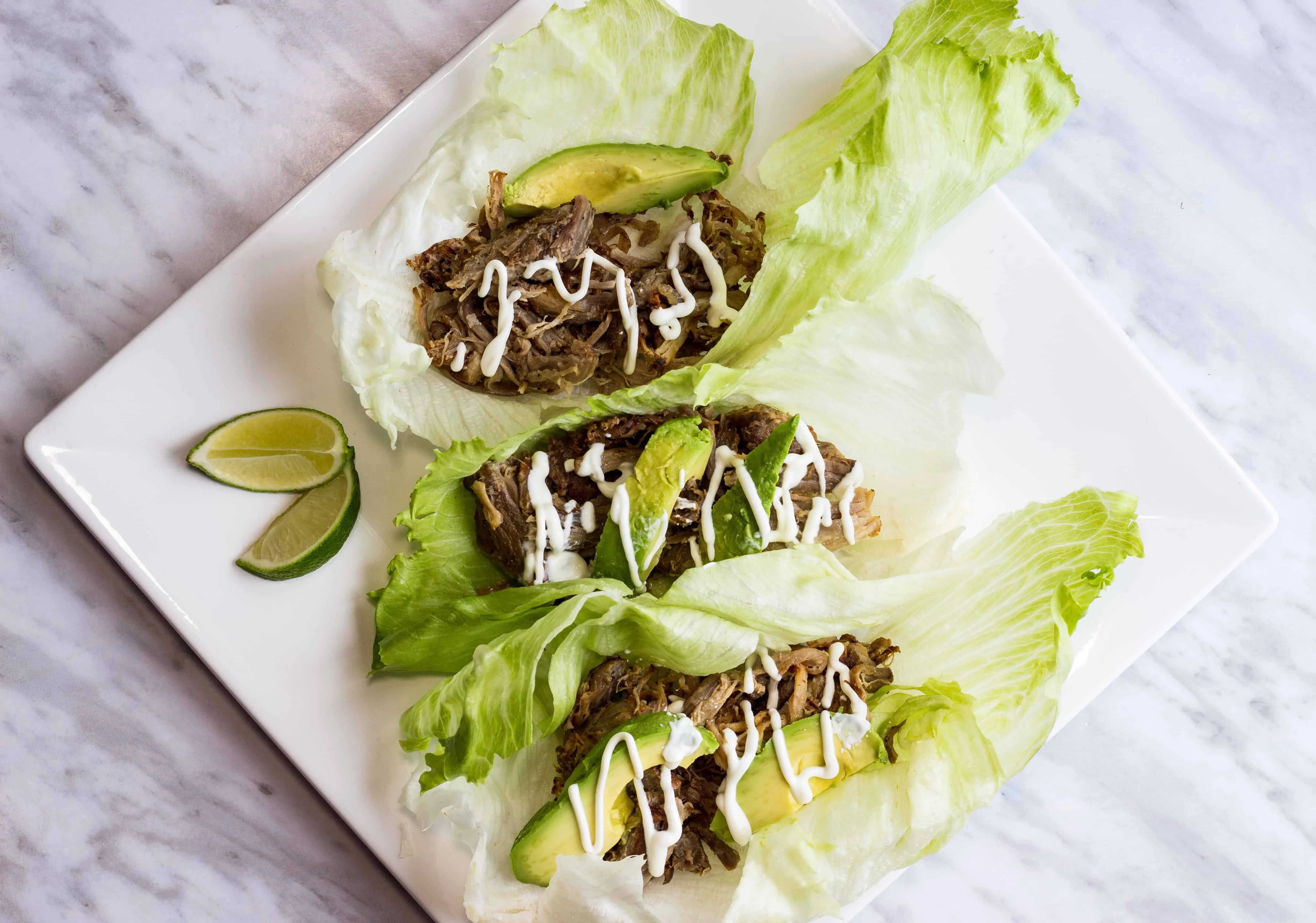 three lettuce wrapped al pastor pork carnitas on a plate