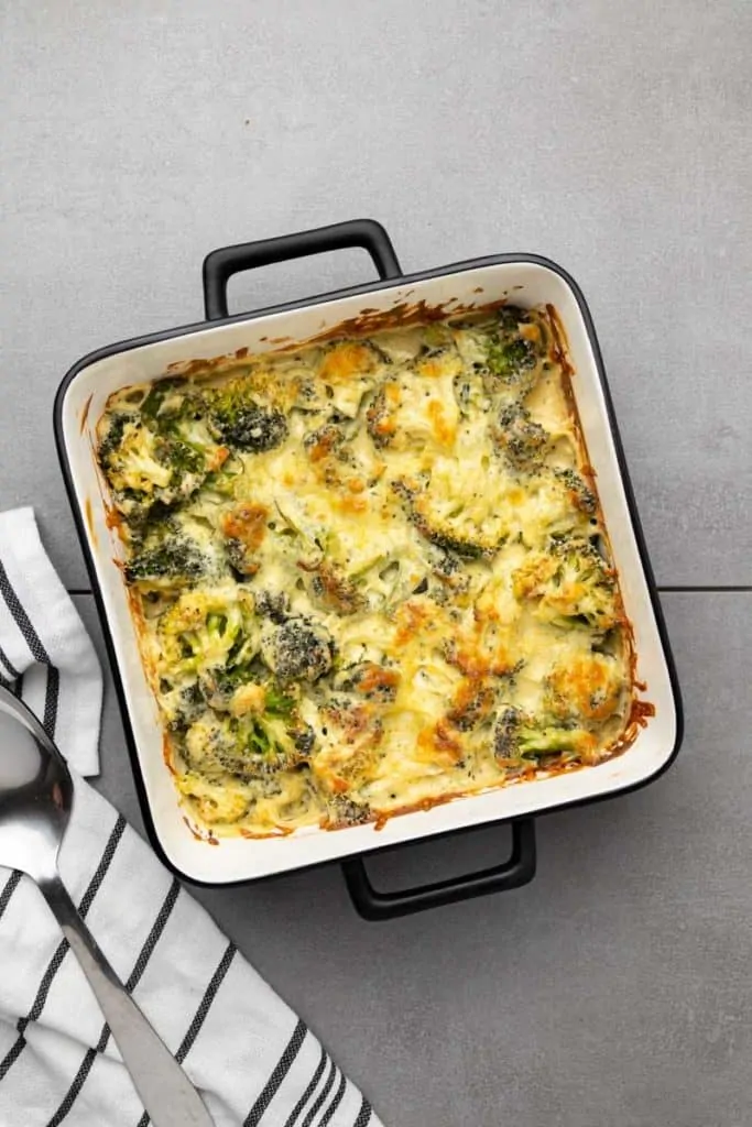 Keto Broccoli Casserole in a square baking dish next to a serving spoon.