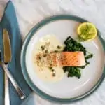 keto salmon with lemon dill cream sauce on a plate with sauteed spinach