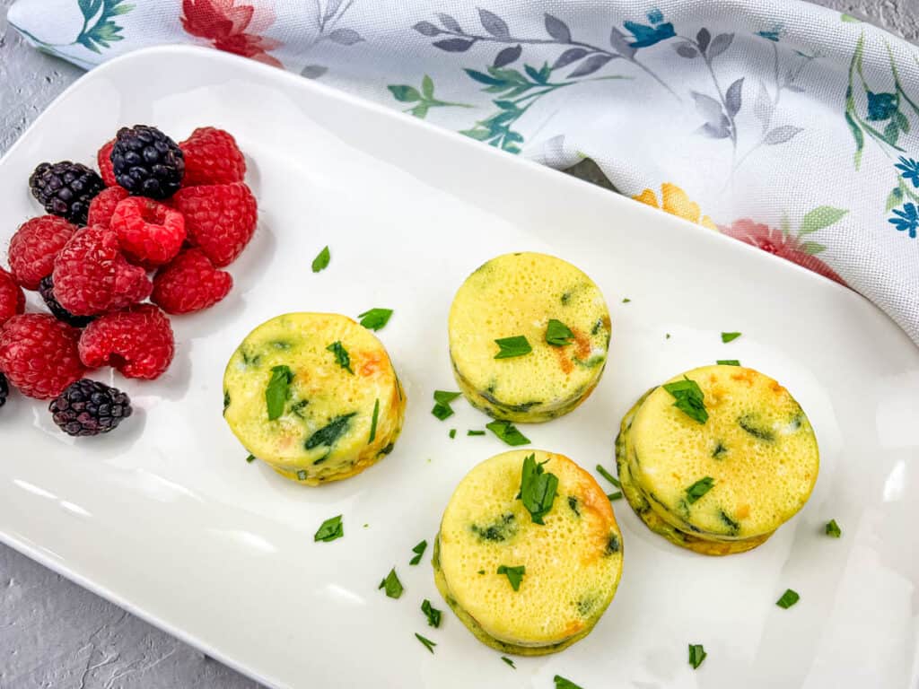 Egg bites with spinach & cheese on a black plate.