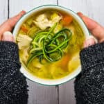 Grandma's Keto Chicken Zoodle Soup in a bowl held between two hands