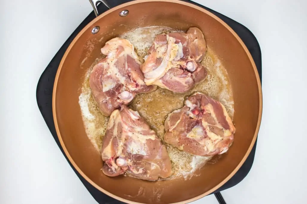 seasoned chicken in a skillet with butter