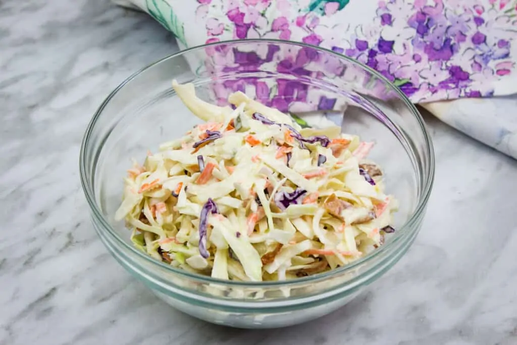 pickle slaw with bacon in a clear glass bowl