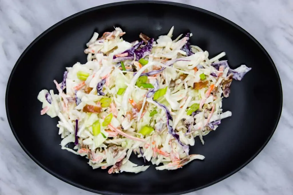 pickle slaw with bacon on a black oval plate