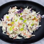 pickle slaw with bacon on a black oval plate