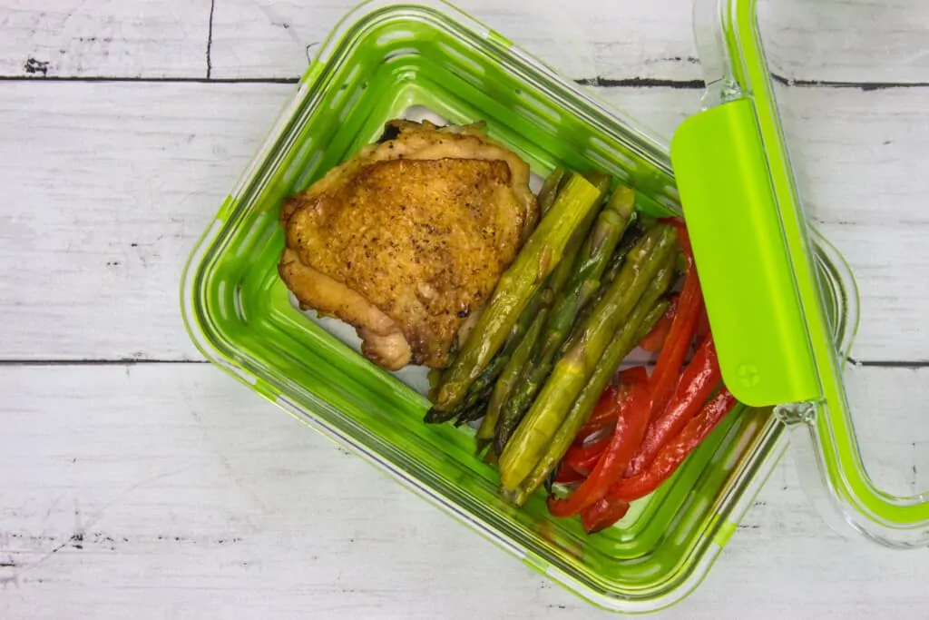 Garlic chicken skillet with asparagus and red bell pepper in a meal prep conatainer
