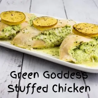 Three chicken breasts, baked with a filling of Green Goddess herbed cream cheese mixture and a slice of lemon on top, resting on a white plate.