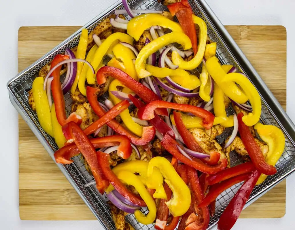 add cut onions and peppers to the top of the chicken and air fry a few more minutes