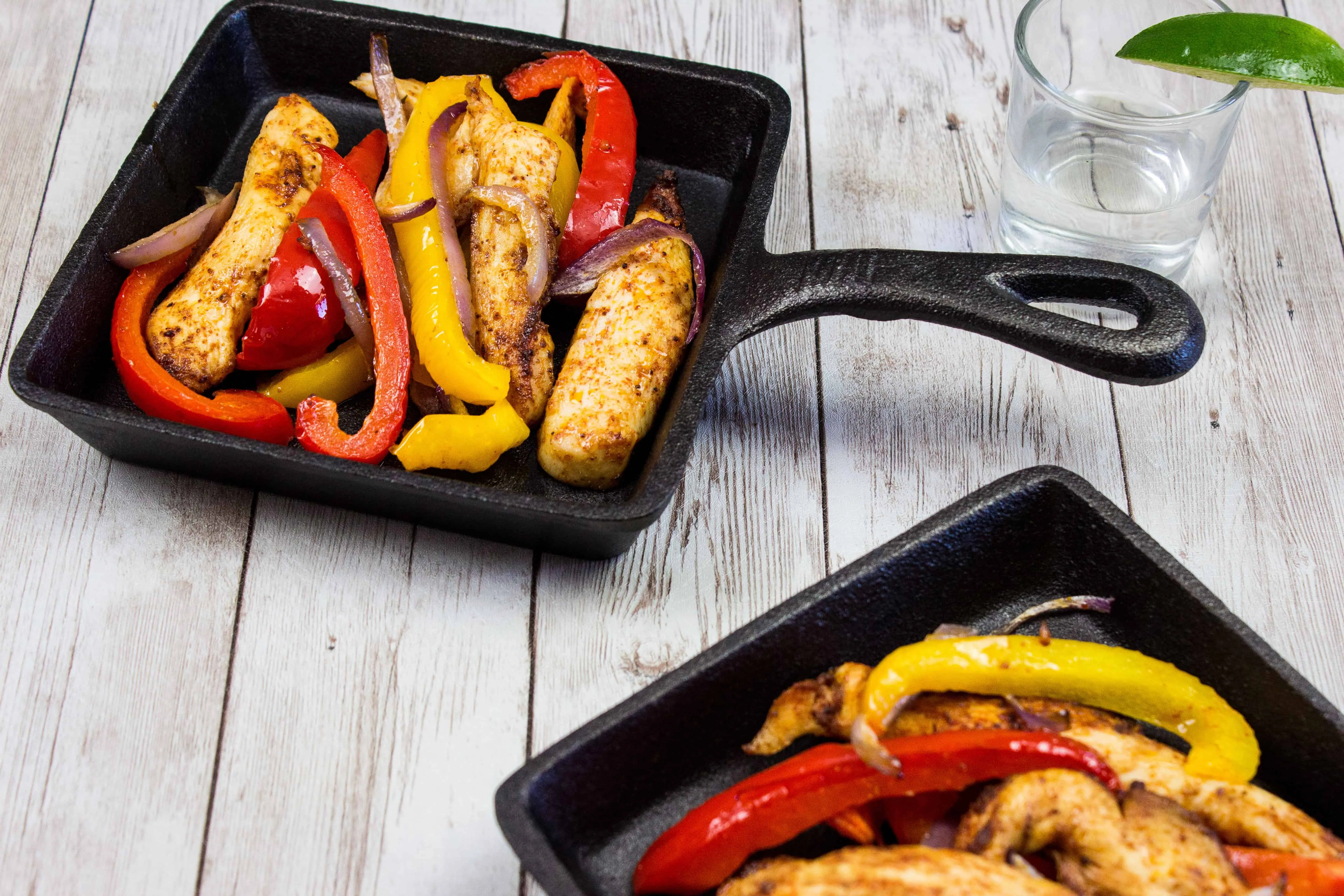 two portions of air fryer fajitas on square cast iron plates