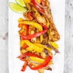 air fryer fajitas on a long white plate with lime wedges