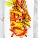 air fryer fajitas on a long white plate with lime wedges