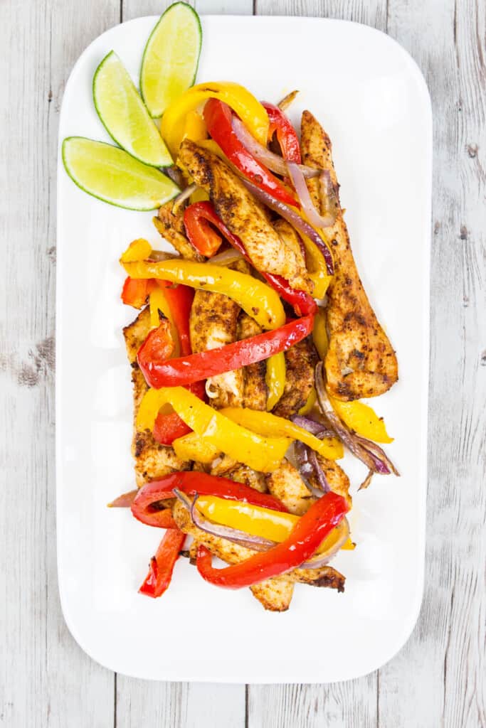 air fryer fajitas on a long white plate with lime wedges