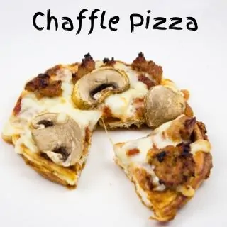 A sausage and mushroom topped chaffle pizza with a wedge shaped slice cut from it resting at a slight offset.