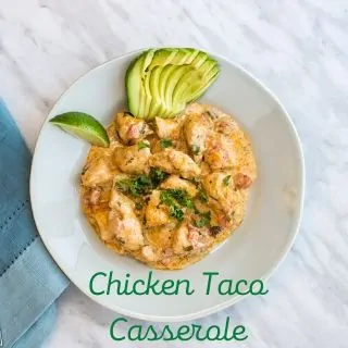 Chicken Taco Casserole served on a round plate with a garnish of sliced avocado and a lime wedge.