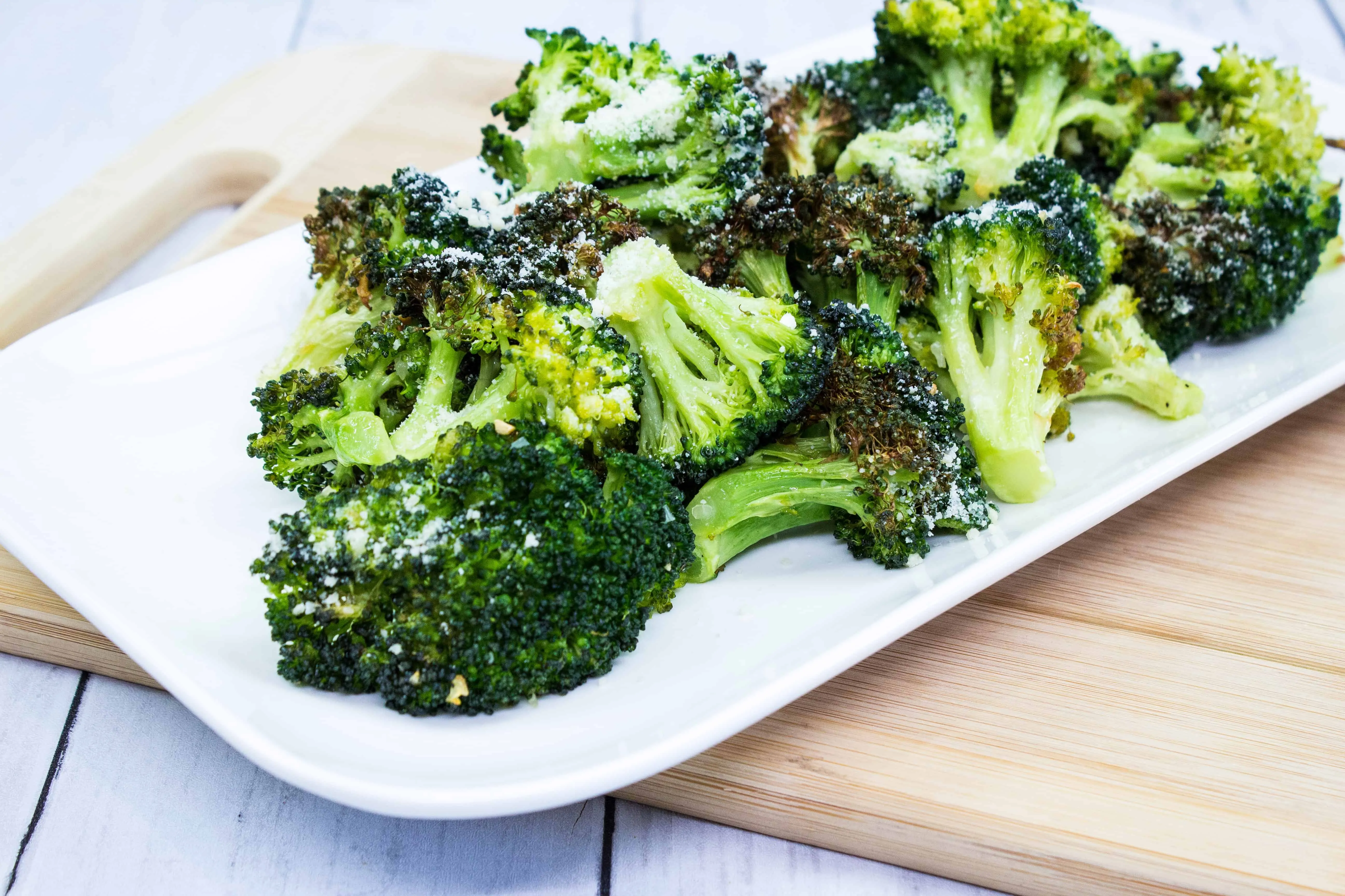 keto broccoli with garlic and parmesan on a white rectangular plate