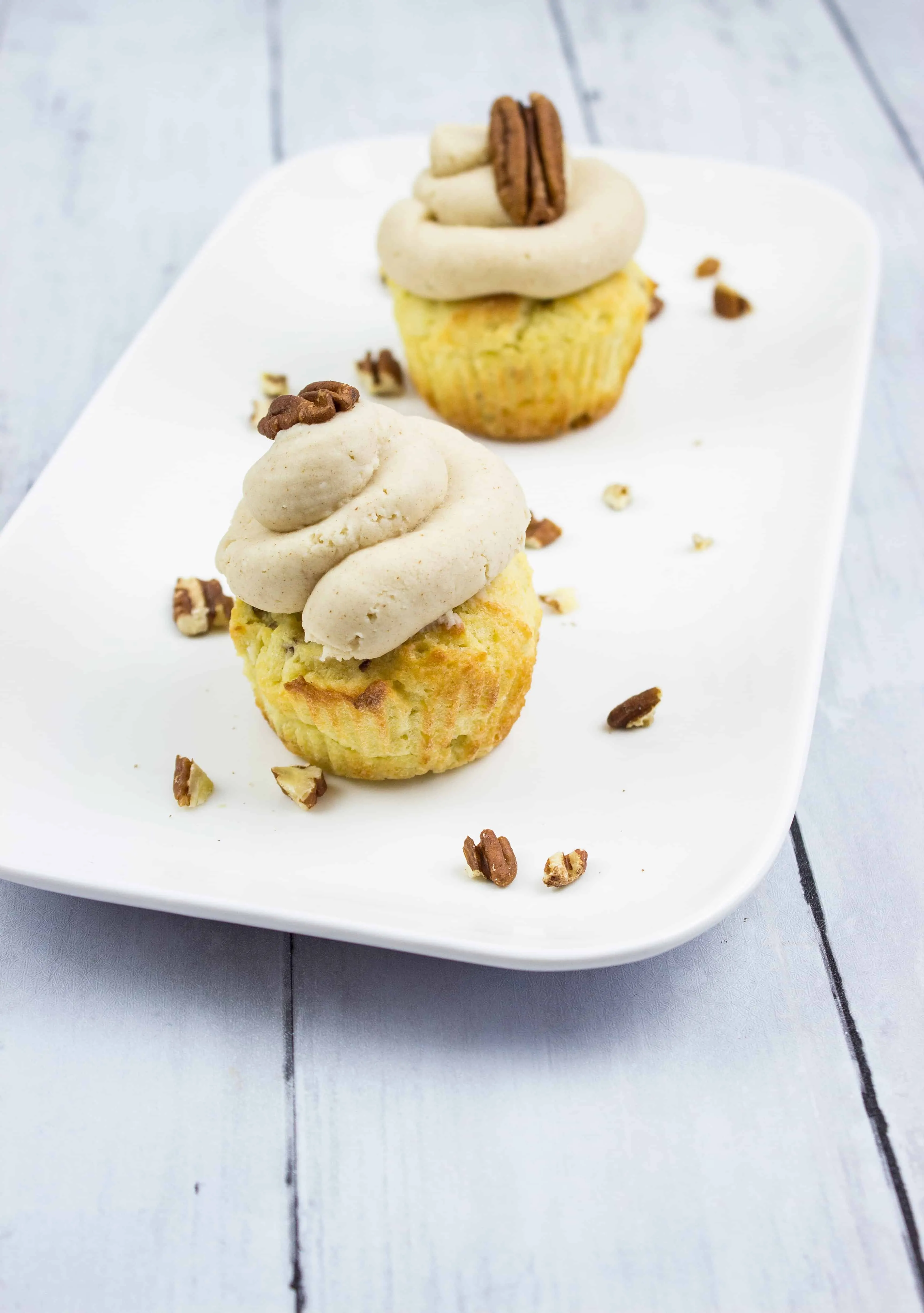 pecan cupcakes with brown butter cream cheese icing on a plate