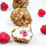 frozen cheesecake bites on a plate with raspberries