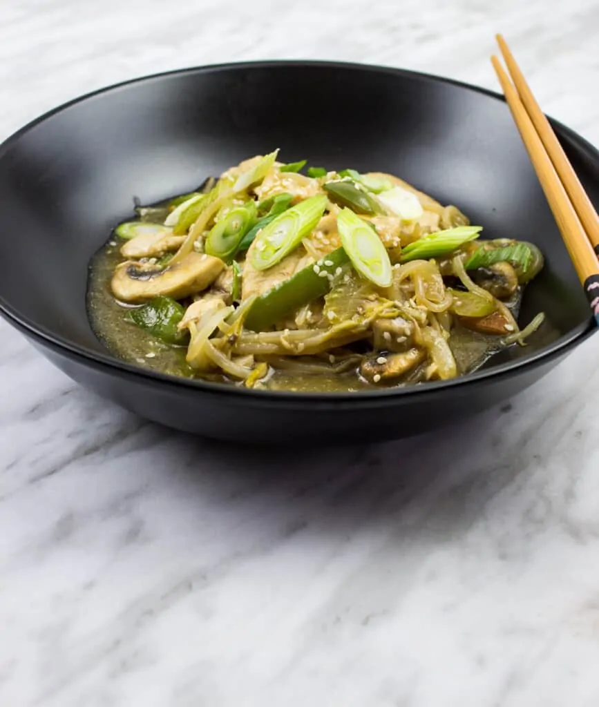 keto chicken stir fry in a black bowl with chopsticks on the side