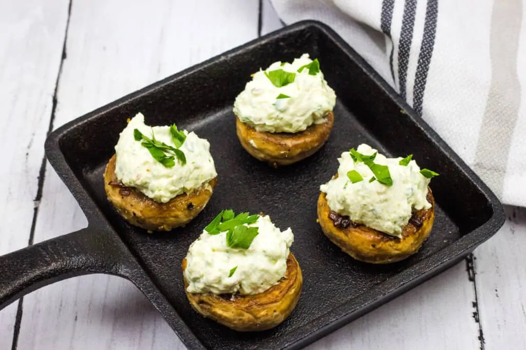 four green goddess stuffed mushroom caps on a square cast iron dish