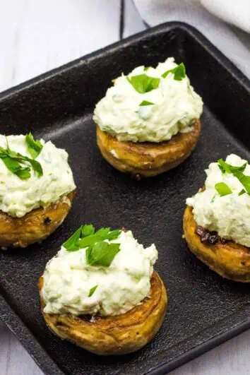 four green goddess stuffed mushroom caps on a square cast iron dish