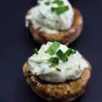 two green goddess stuffed mushroom caps on a black background