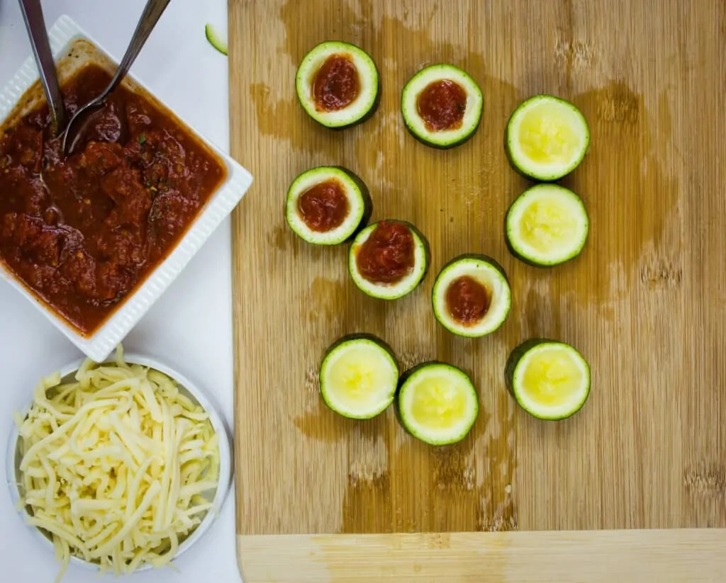 scooping out the middle of the zucchini and filling with sauce