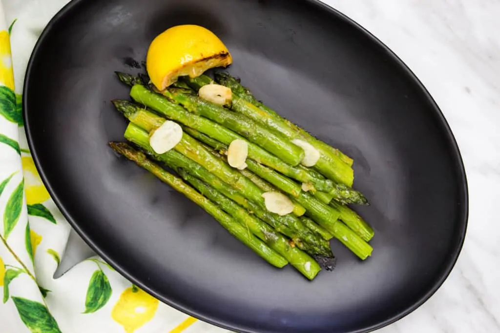 keto pan roasted asparagus with lemon on a black plate