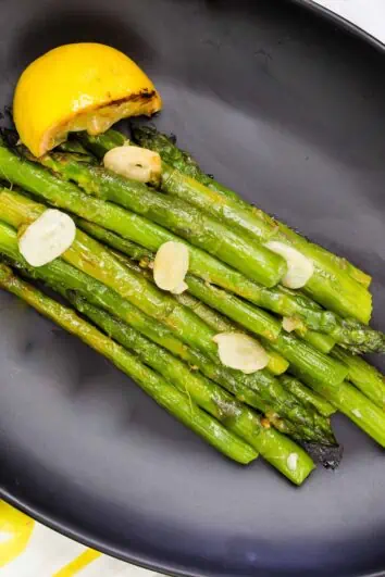 keto pan roasted asparagus with lemon on a black plate