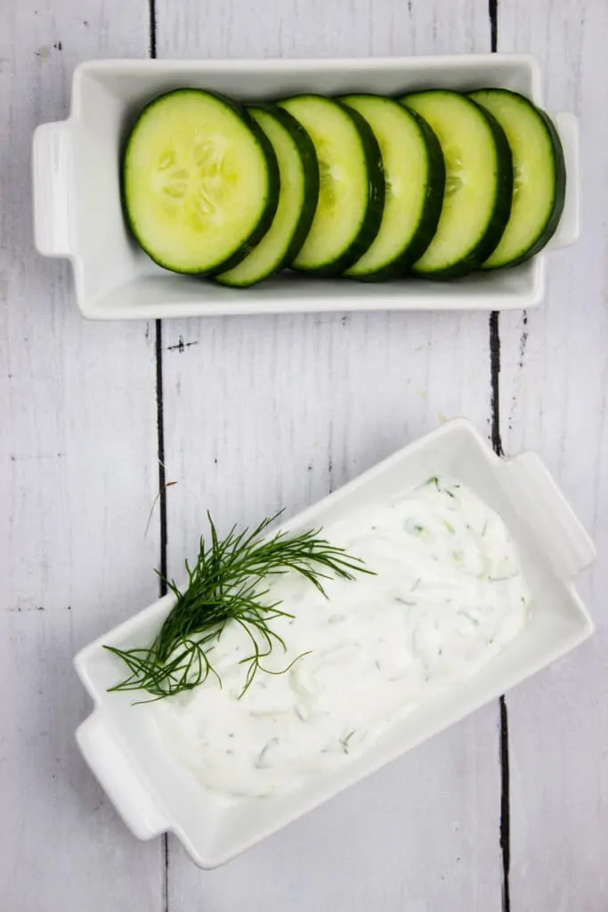 tzatziki sauce keto in a dish with sliced cucumbers on the side