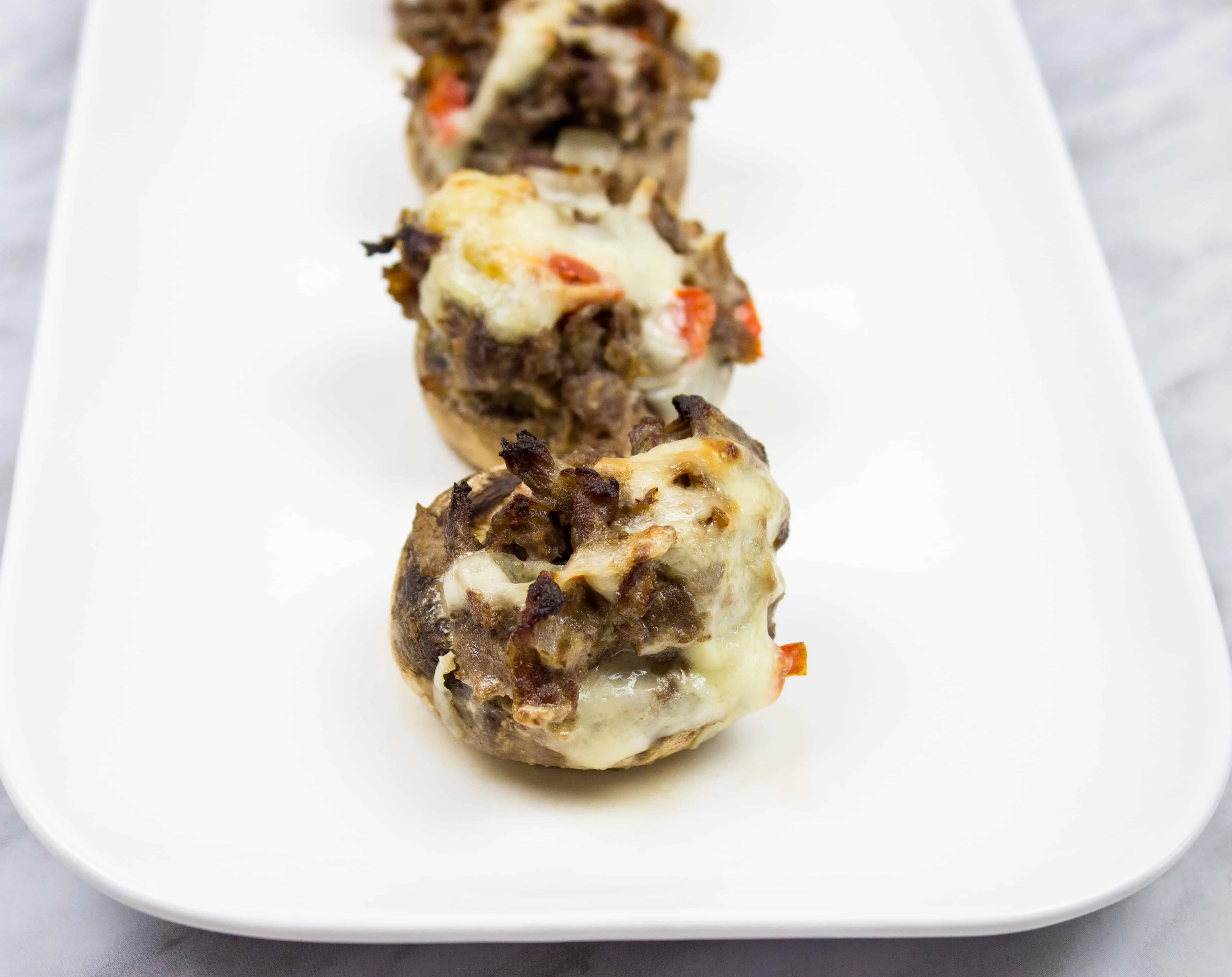 keto philly cheesesteak stuffed mushroom caps on a serving plate