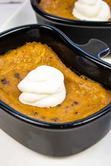 keto pumpkin custard in a black ramekin with a dollop of whipped cream