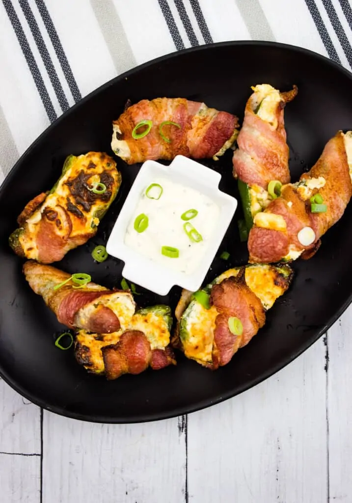 ranch keto jalapeno poppers on a black oval plate with sauce