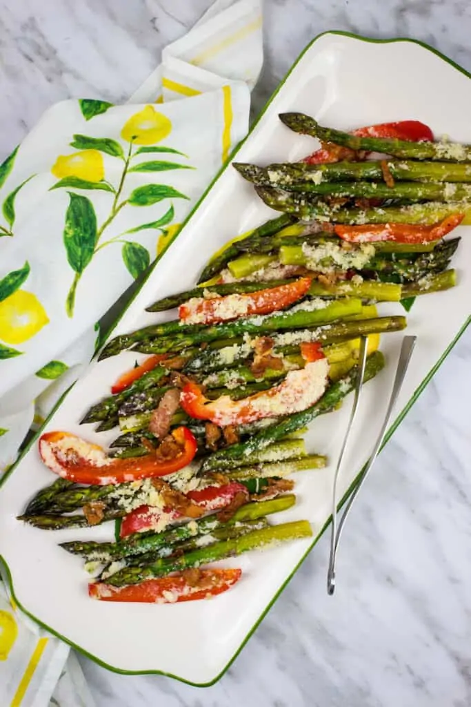 keto cheesy baked asparagus with bacon and peppers on a white serving platter