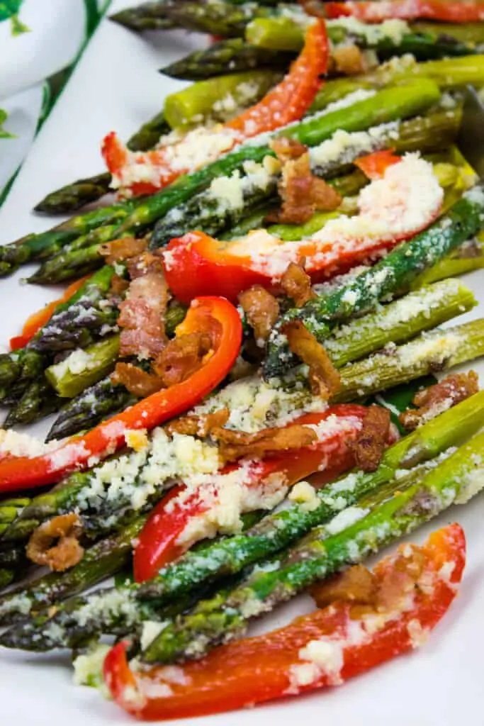 a closeup of keto cheesy baked asparagus with red peppers and bacon