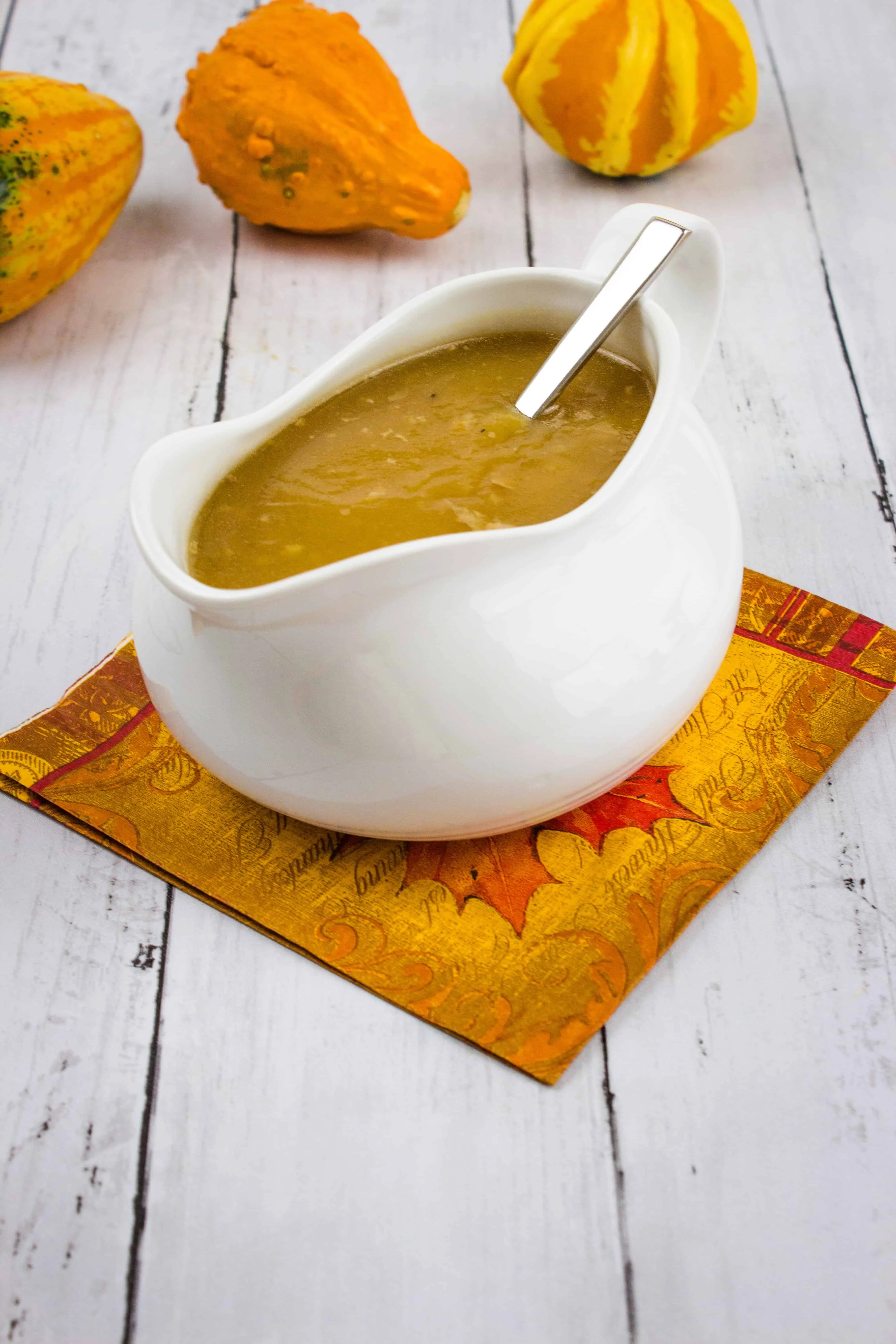 Keto Turkey Gravy in a gravy boat with gourds in the background