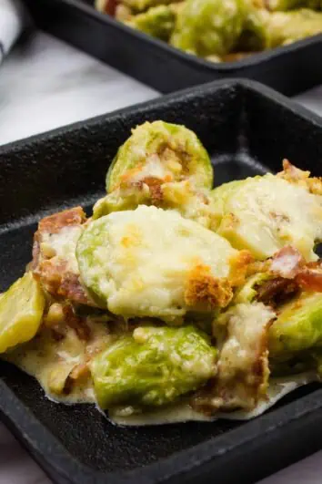 keto parmesan brussels sprouts with bacon in a black cast iron serving dish