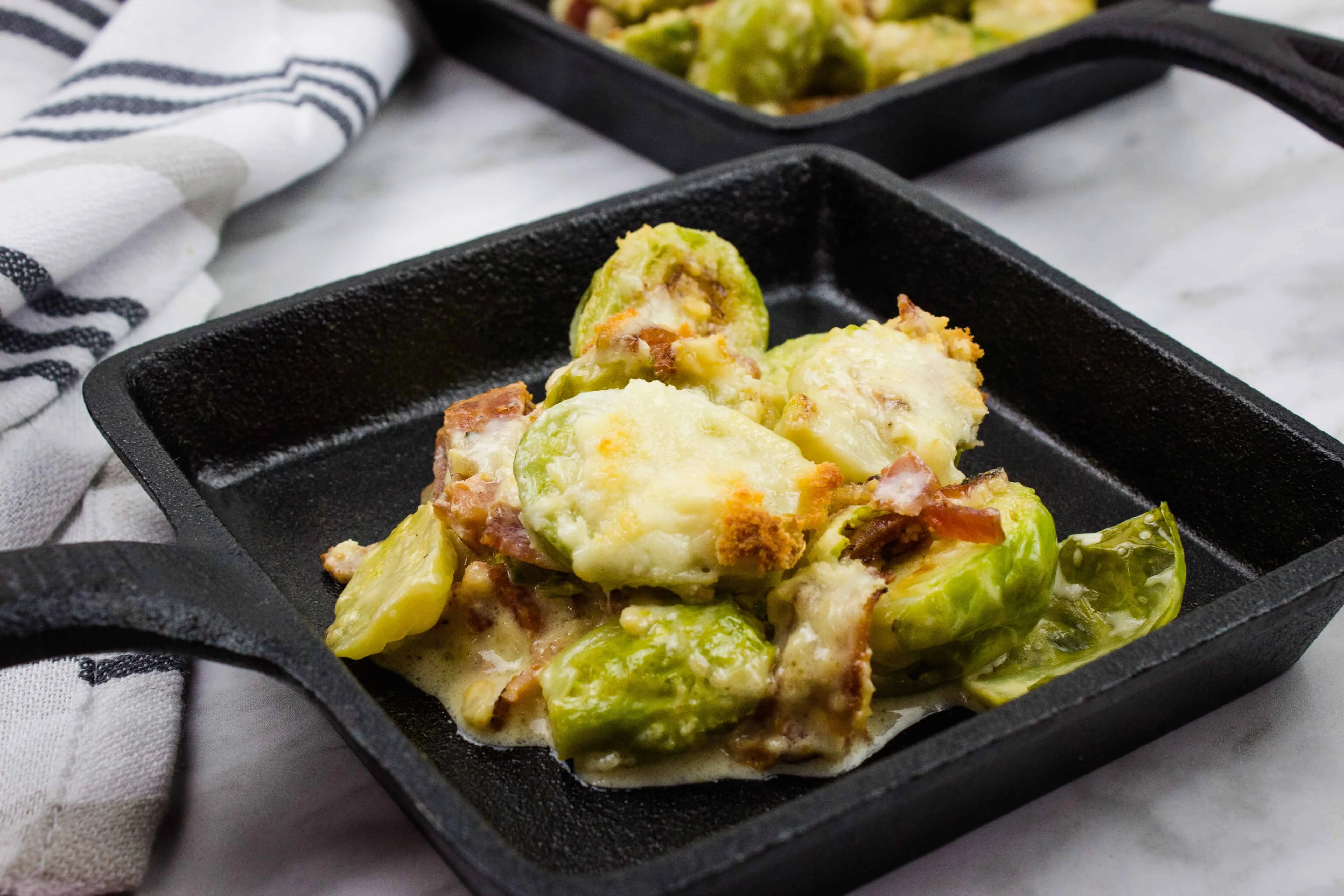 keto parmesan brussels sprouts with bacon in a black cast iron serving dish