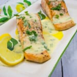 salmon with lemon-herb butter sauce on a platter