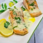 salmon with lemon-herb butter sauce on a platter