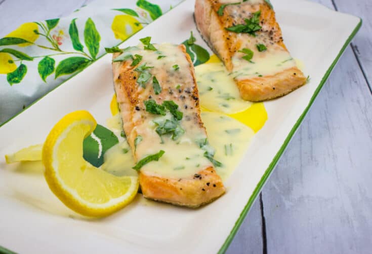 salmon with lemon-herb butter sauce on a platter
