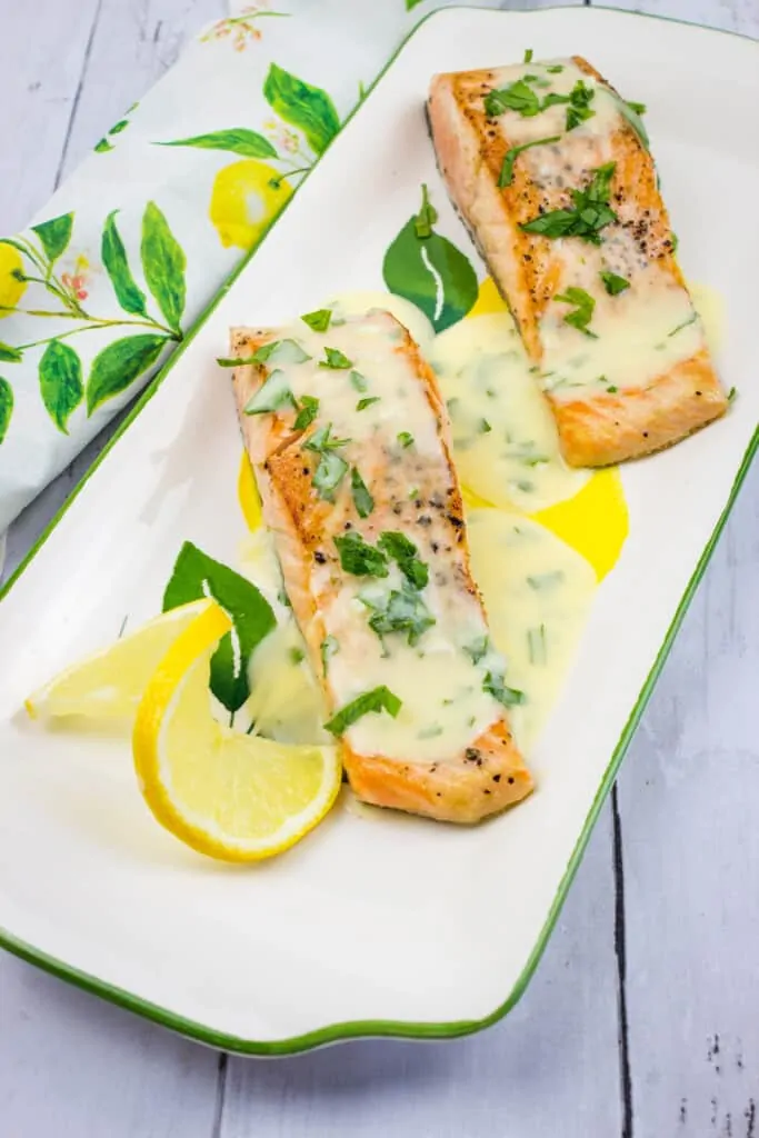 salmon with lemon-herb butter sauce on a platter