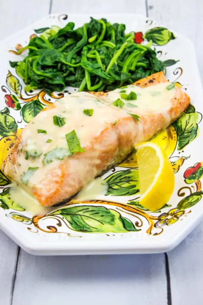 keto salmon with lemon herb butter sauce and spinach on a plate