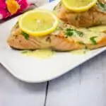 salmon with lemon-herb butter sauce on a platter