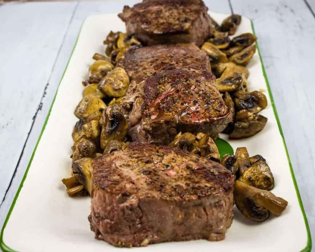 beef tenderloin steaks with mushrooms on a platter