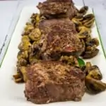 beef tenderloin steaks with mushrooms on a platter