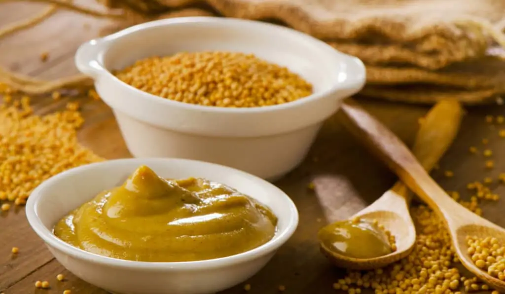 mustard and mustard seeds on a wooden table