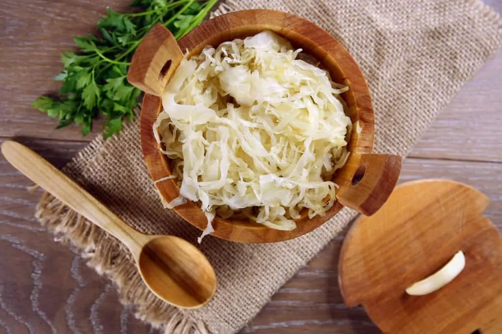 sauerkraut in a wood serving barrel with spoon nearby
