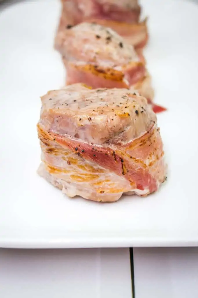 bacon wrapped pork tenderloin on a platter