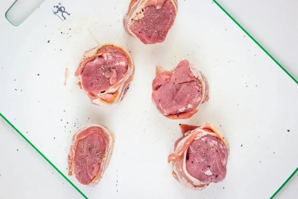 bacon-wrapped pork tenderloin on a cutting board