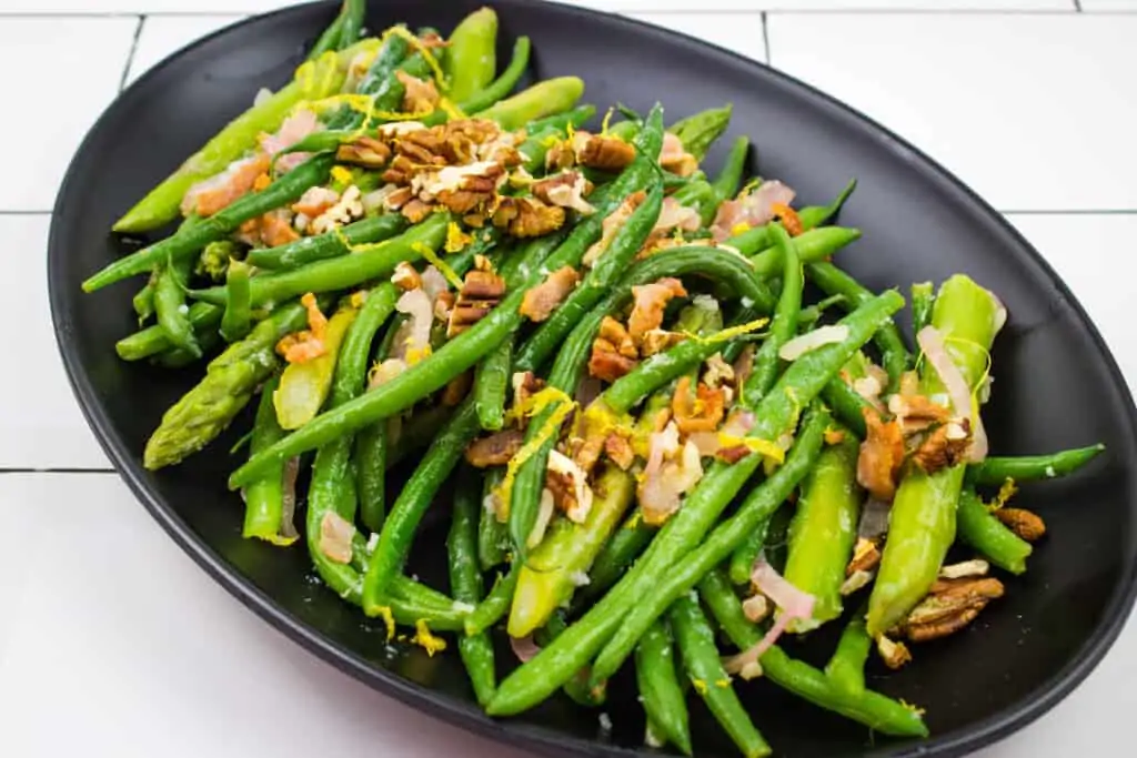 keto green beans & asparagus with lemon & Pecans on a black serving platter